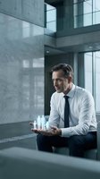 Professional businessman holding holographic family figures in modern office building representing work-life balance and corporate responsibility concepts.