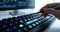 Professional typing on illuminated keyboard with financial charts on monitor screen showing market data analysis and digital trading workspace setup.