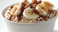 Bowl of oatmeal topped with sliced bananas, almonds, and caramel drizzle for breakfast, healthy eating, and nutrition content.