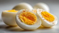 Hard-boiled eggs cut in half showing bright yellow yolks with sprinkled paprika on a light surface, perfect for healthy meal preparation.