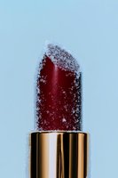 Luxury red lipstick covered in white powder against soft blue background for beauty and cosmetics advertising campaigns.