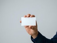 Hand holding blank white business card against neutral background, ready for branding and contact information design.