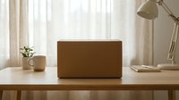 Cardboard box on a wooden desk with a lamp, plant, and mug in a bright home office setting, symbolizing delivery and moving.
