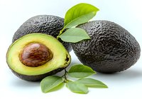 Fresh ripe avocados with green leaves, one cut in half showing brown pit and creamy flesh against white background, healthy organic produce for food design.