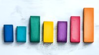 Colorful wooden blocks arranged in ascending order on white background showing growth concept, business progress chart made of rainbow colored elements.