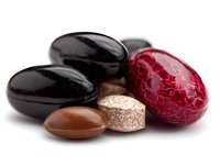 Assorted chocolate candies and pralines with dark chocolate coating and red foil wrapper on white background, macro food photography for confectionery advertising.