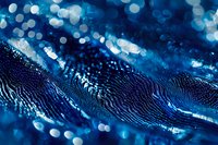 Abstract macro photography of water droplets creating wave-like pattern with blue bokeh lights in background, showcasing natural fluid dynamics and light refraction.