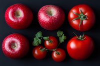 Fresh red apples and tomatoes arranged on dark background, showcasing vibrant colors and natural textures for food and healthy eating concepts.