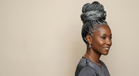 Young Black woman with gray braided updo hairstyle wearing dark shirt, isolated on neutral background. Suitable for beauty, hair care, fashion, and lifestyle design projects.