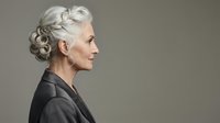 Senior woman with gray hair in elegant updo, wearing black jacket, isolated on neutral background for portrait and professional use.