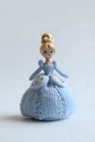 Handcrafted knitted doll in blue princess dress with blonde hair bun, standing against white background for children's decor or collectibles.