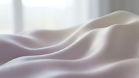 Soft flowing white silk fabric with elegant waves and gentle curves creating luxurious textile background for fashion and interior design projects.