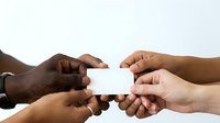 Diverse group of people holding blank white business card together, teamwork and collaboration concept for corporate networking and partnership projects.