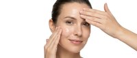 Young Caucasian woman applying facial cream with hands on white background for skincare routine and beauty treatment concepts.
