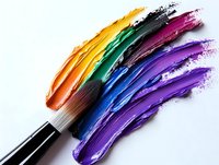 Paint brush creating vibrant rainbow strokes of yellow, green, blue and purple paint on white background, artistic close-up composition for creative design projects.