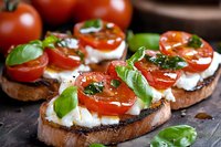 Bruschetta with fresh mozzarella, cherry tomatoes and basil leaves on toasted bread drizzled with balsamic glaze, close up view on dark background.