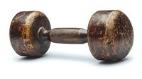 Vintage rusty dumbbell with weathered metal surface showing age and wear, fitness equipment for strength training and bodybuilding workouts.