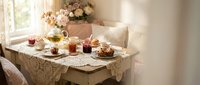Elegant afternoon tea setup with vintage lace tablecloth, floral teapot, pastries and jam jars in cozy sunlit room for hospitality dining concepts.