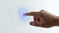 Hand touching futuristic holographic interface with glowing blue circular element on transparent digital screen for modern technology applications.