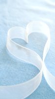 White satin ribbon forming heart shape on soft blue textured background for romantic wedding Valentine's Day love celebration greeting card design.