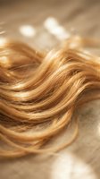 Flowing golden blonde hair strands with warm highlights creating soft waves and natural texture for beauty and haircare concepts.