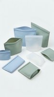 Reusable silicone food storage bags in blue and green colors arranged on white background for zero waste kitchen organization and meal prep.