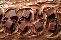 Melted chocolate swirls with broken dark chocolate pieces creating rich texture and decadent pattern, food photography for dessert and confectionery marketing.