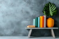 Colorful books arranged on wooden bench with monstera leaf in orange ceramic vase against textured gray wall, modern minimalist home decor styling.