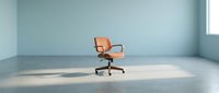 Modern orange office chair with wooden armrests positioned in minimalist empty room with concrete floor and natural light from window.