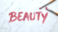 Cosmetic brushes with pink paint strokes forming text on marble surface, representing makeup artistry and beauty industry branding for cosmetics, skincare and salon design projects.