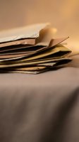 Stack of aged vintage newspapers with warm golden lighting creating nostalgic atmosphere for media and journalism projects.