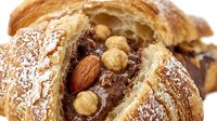 Freshly baked croissants dusted with powdered sugar, filled with chocolate and roasted almonds, perfect for bakery, cafe, and food photography projects.