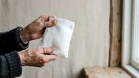 Senior adult with medium skin tone holding white tissue paper, suitable for healthcare, wellness, cold and flu prevention, allergy relief, and medical awareness campaigns.