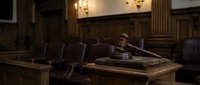 Wooden gavel rests on sound block in elegant courtroom with leather chairs and warm lighting. Legal proceedings and justice system concept.