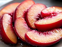 Sliced red peaches with glistening wet surface arranged on dark plate, showcasing juicy fresh fruit texture and natural sweetness for food photography and culinary design projects.