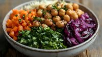 Healthy Buddha bowl with roasted chickpeas, fresh spinach, diced carrots, purple cabbage and quinoa. Nutritious vegetarian meal for clean eating lifestyle.