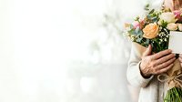 Mature man holding bouquet of peach roses and mixed flowers with greenery, wearing beige sweater. Suitable for greeting cards, celebrations, and romantic occasions.