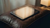 Tablet computer resting on brown leather surface with warm natural light, suitable for technology, business, and digital device concepts.