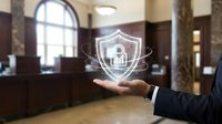 Businessman hand presenting digital security shield with lock icon in elegant bank lobby interior for cybersecurity and data protection concepts.