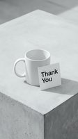 White ceramic mug with a Thank You note card on a concrete surface, monochrome minimalist style for business and gratitude concepts.