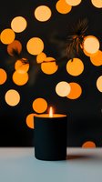 Glowing candle against dark background with orange bokeh lights creating magical atmosphere. Cozy holiday mood for seasonal greeting cards and decor.