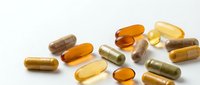 Various dietary supplements and vitamins in capsules and soft gels scattered on white background for health and wellness concepts.
