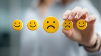 Yellow emoji faces showing different moods from happy to sad, with business person selecting sad face on transparent glass surface. Customer satisfaction concept.