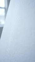 Close-up of white textured wall surface with natural window light creating soft shadows and architectural details for interior design projects.