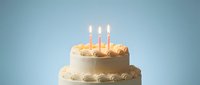 Two-tier vanilla birthday cake with lit candles on blue background for celebration party dessert bakery menu design.