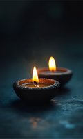 Two traditional oil lamps burning with warm flames on dark textured surface creating peaceful ambiance for meditation and spiritual practices.