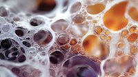 Macro photography of soap bubbles in orange and purple gradient colors creating abstract pattern with delicate foam texture and translucent spherical shapes.