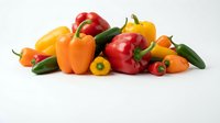 Fresh assorted bell peppers and hot chili peppers in red, yellow, and orange colors arranged on white background for cooking and recipe content.