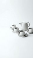 Modern minimalist white ceramic tea set with teapot and cups on saucers arranged on clean white background for contemporary kitchen and dining concepts.