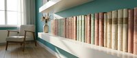 Modern home library interior with colorful book collection on white floating shelves against teal wall, minimalist reading nook with wooden chair.